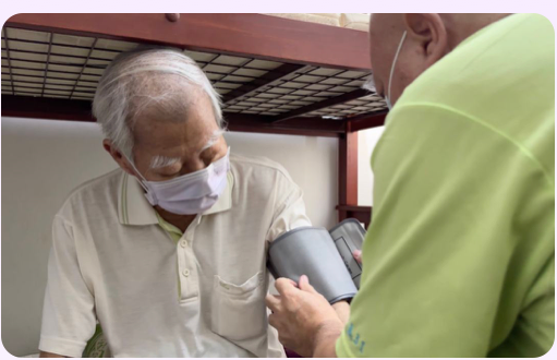 A health worker taking an elderly man's blood pressure at a community clinic